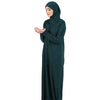 Una mujer vistiendo una elegante caftán de abaya islámica verde oscuro con hijab.