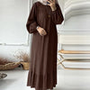 Une femme portant une longue robe maxi bohème marron foncé avec un ourlet froncé et un hijab beige clair.