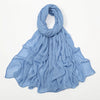 Écharpe châle en rayon bleu clair froissé drapée et pliée sur fond blanc.