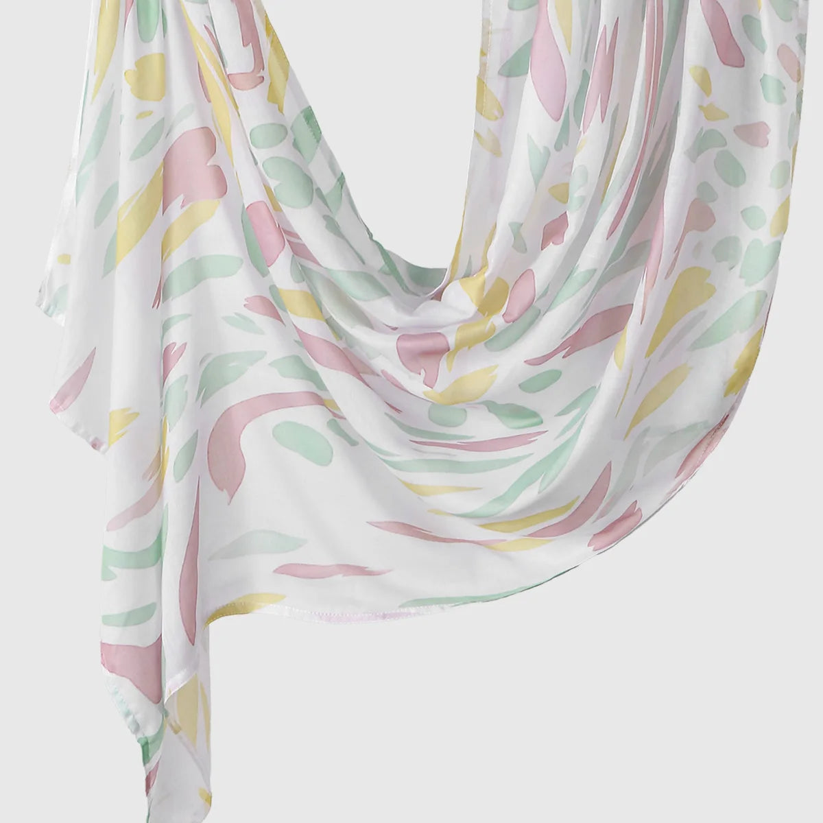 Elegant printed linen hijab scarf featuring a watercolor floral pattern in pink, yellow, and green on a white background.