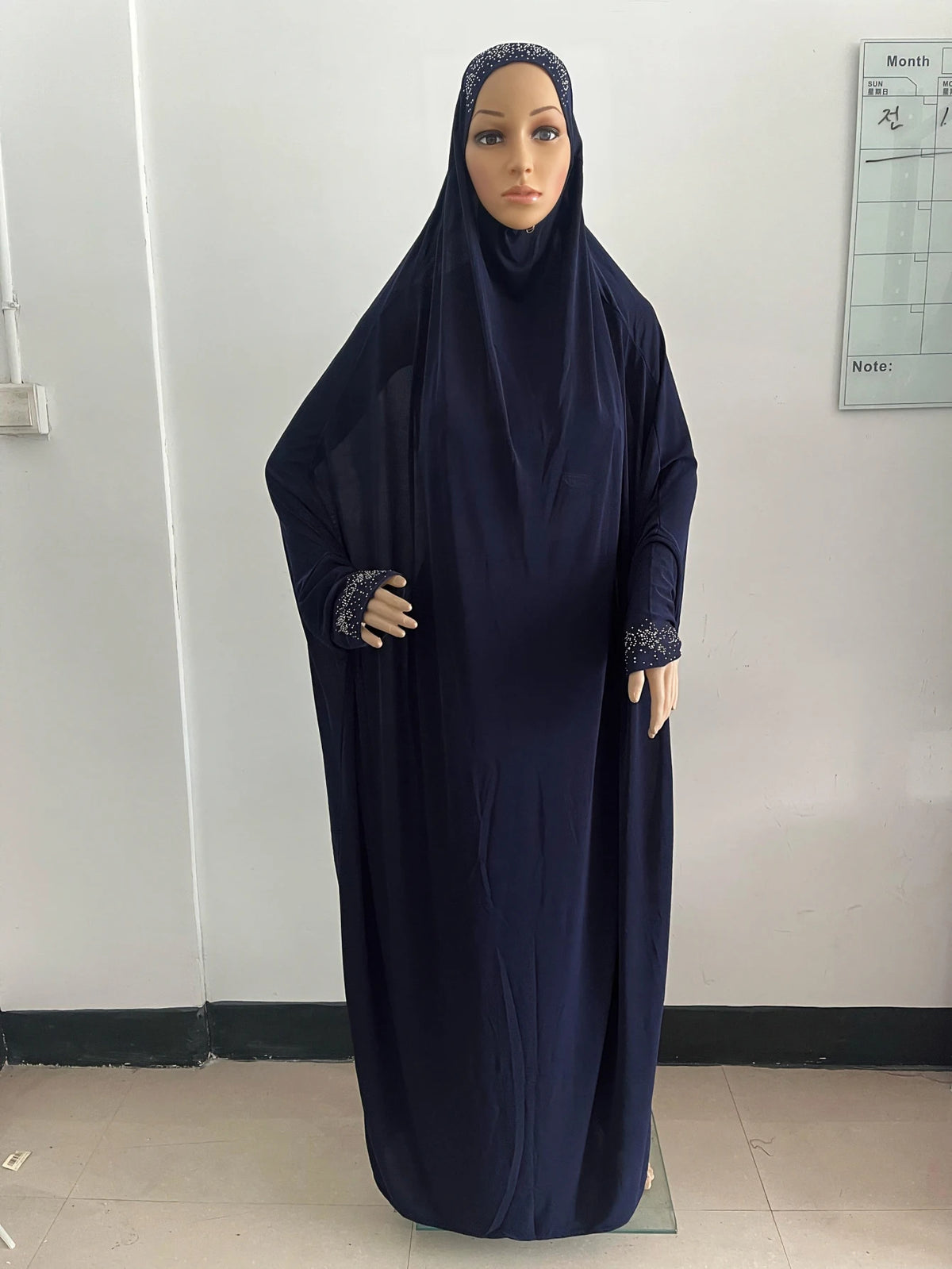 Une longue caftan abaya bleu foncé et fluide portée par un mannequin.
