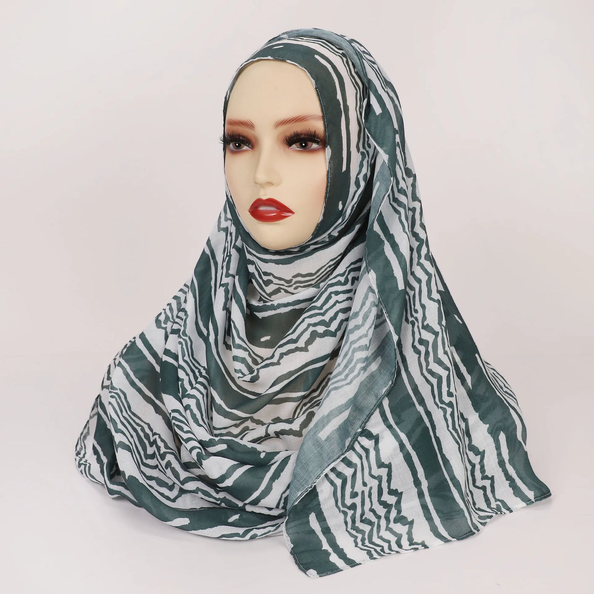 Una mujer modela un pañuelo hijab de estampado leopardo acuarela bohemio en tonos verdes y blancos.
