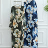 Dunkelblaue und weiße florale Abaya auf einem Kleiderbügel vor einer weißen Wand.