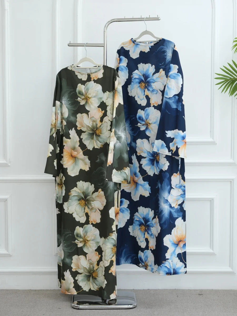 Dunkelblaue und weiße florale Abaya auf einem Kleiderbügel vor einer weißen Wand.