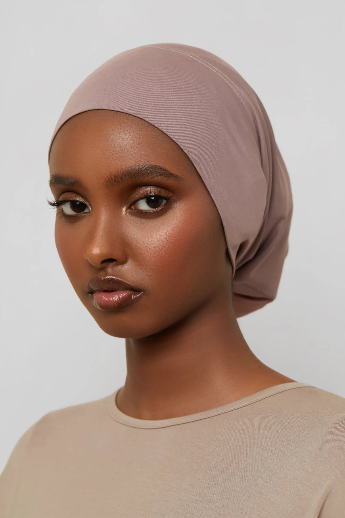 Model wearing a beige bamboo jersey tube hijab cap with natural skin tone.