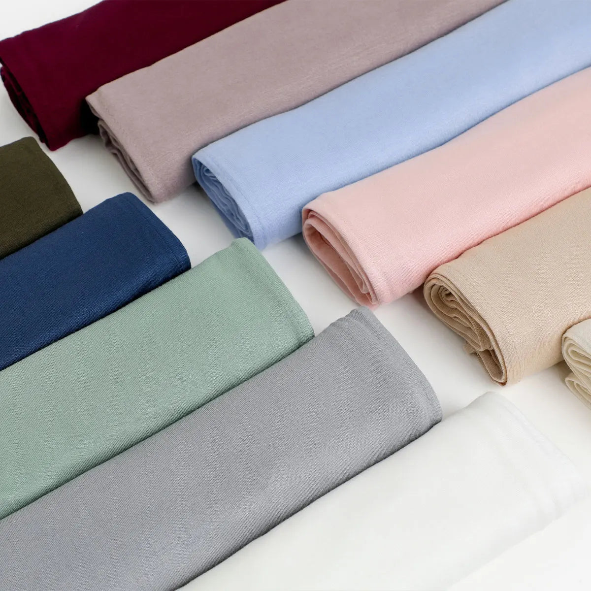 Eine Kollektion eleganter Chiffon-Schals oder Überwürfe in verschiedenen Farbtönen wie Lila, Beige, Blau und Grün.