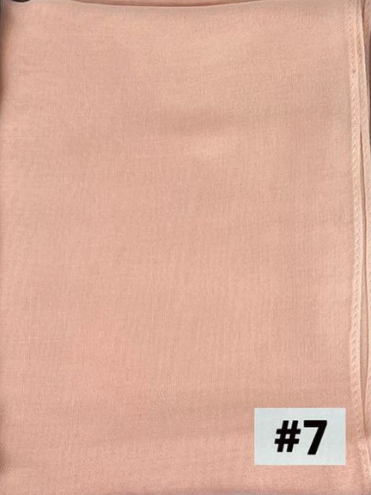 Foulard modal de couleur pêche doux plié et présenté sur un fond blanc.