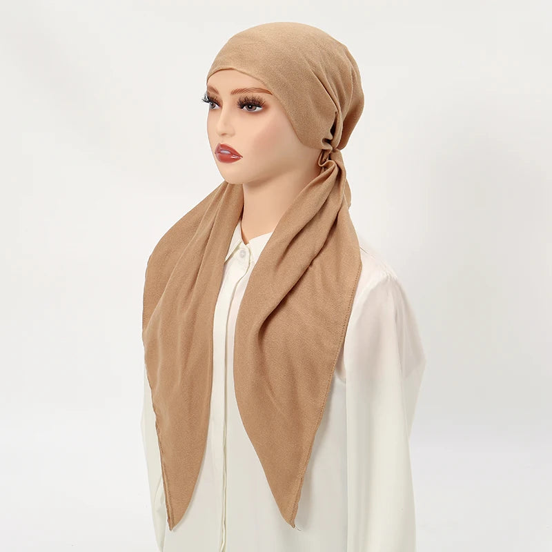 Une femme modèle un bonnet de hijab en lin beige drapé autour de son cou, associé à un haut blanc.