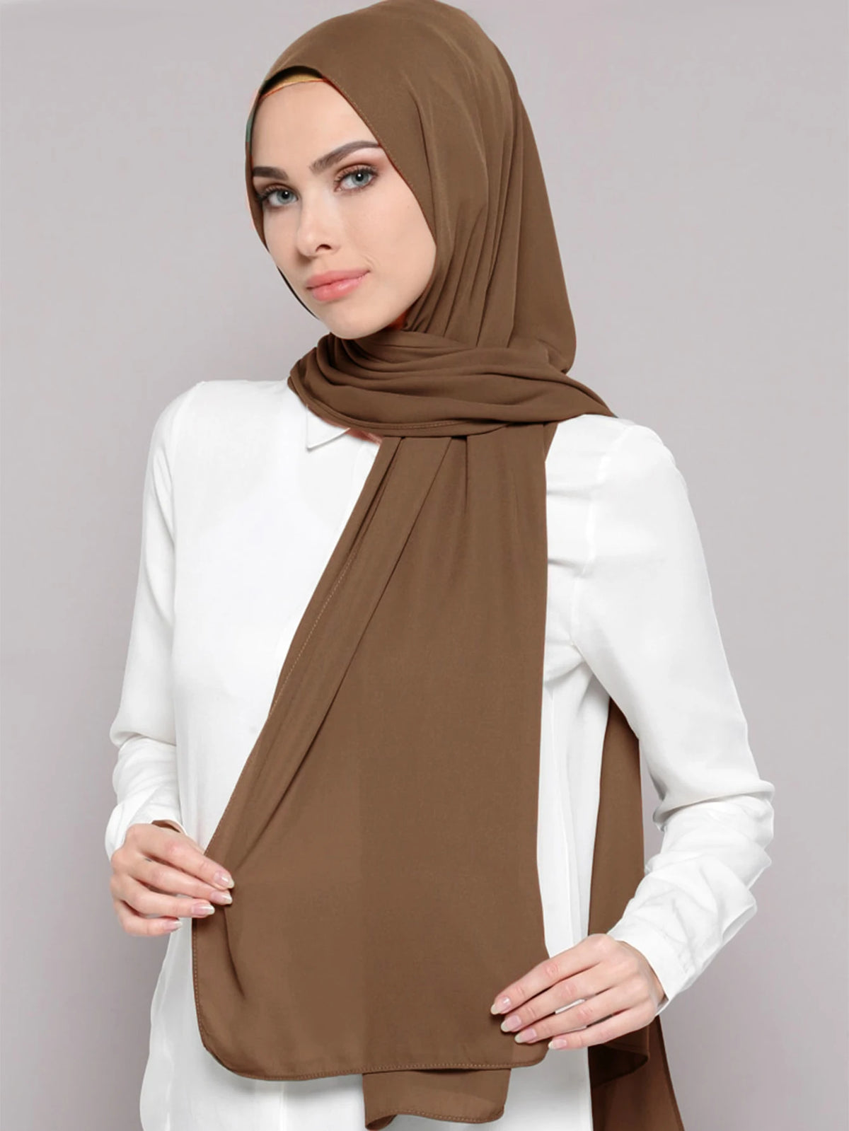 A woman wearing a brown chiffon matching inner scarf set with a white top.