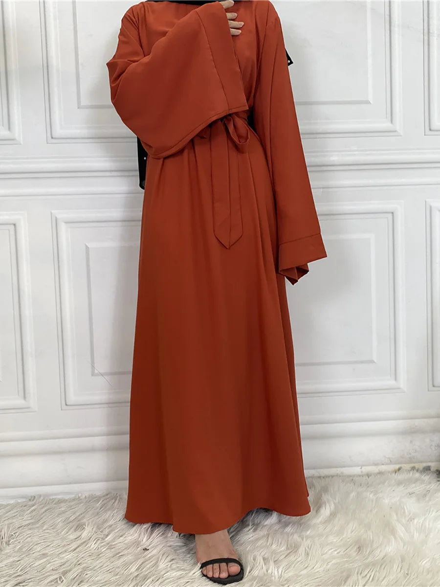 Eine Frau in einem eleganten, langärmeligen, rostfarbenen Maxi-Abaya-Kleid.