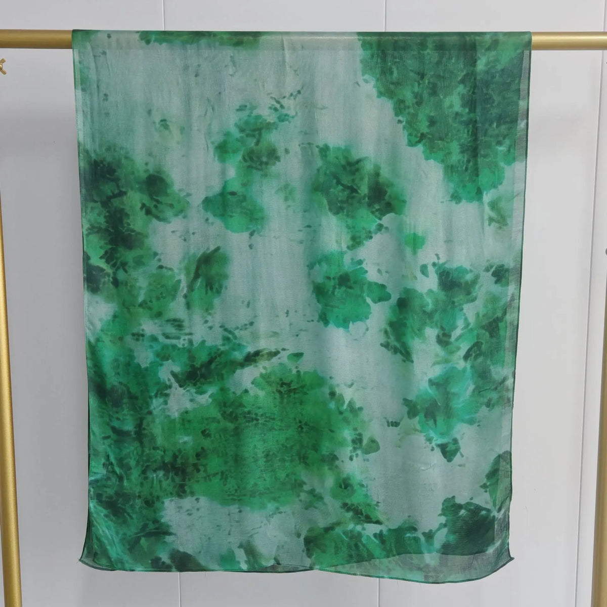 Durchsichtiger grün-weißer Aquarellschal, drapiert auf einem goldenen Haken.