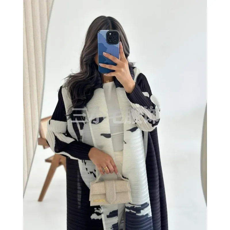 Une femme modélise une veste coupe-vent plissée à imprimé rétro noir et blanc avec un sac à main beige clair.
