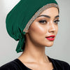 Eine Frau trägt eine elegante smaragdgrüne Hijab-Kappe mit einem funkelnden Strassband und einem schwarzen Kleidungsstück.