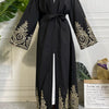 Abaya kaftan de lujo negra con bordado dorado y hijab negro usada por una modelo.