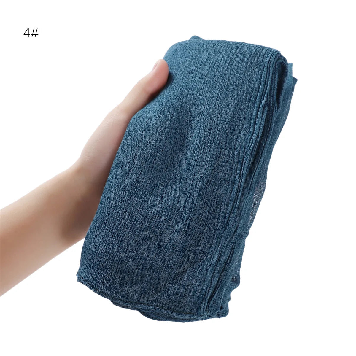 Une main tient un châle foulard en rayon crêpe bleu sarcelle foncé pour femmes.