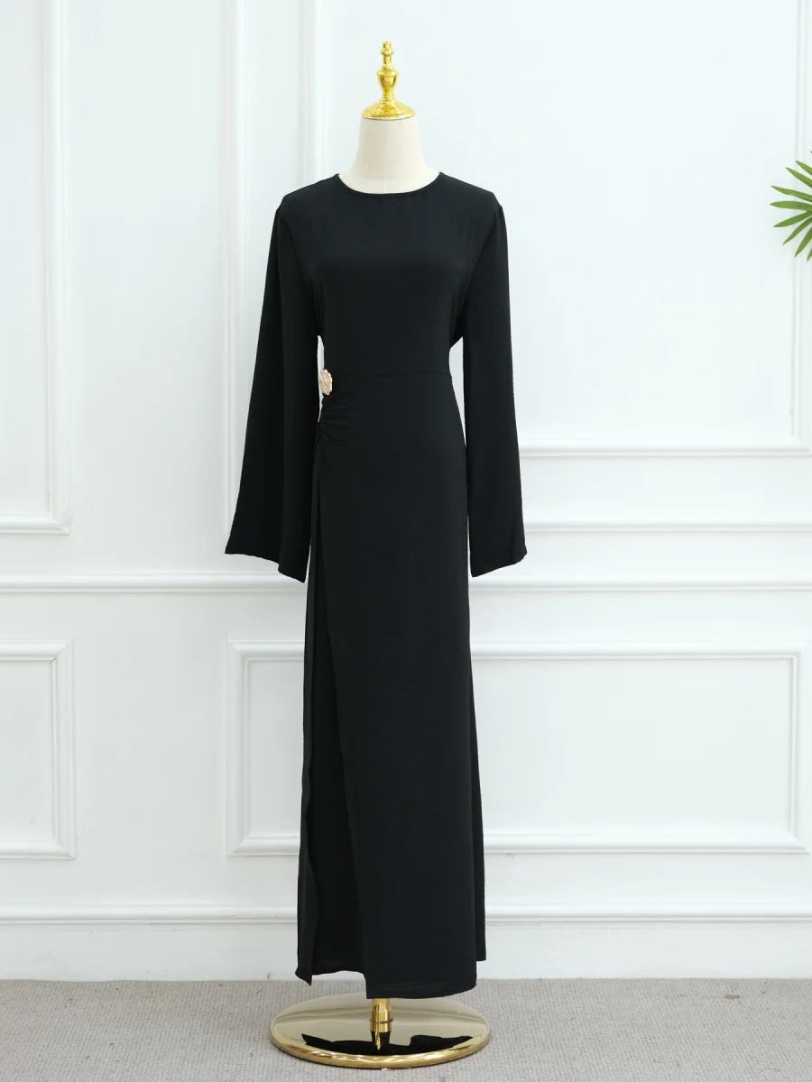 Une abaya noire élégante à cordon de serrage, présentée sur un mannequin devant un mur blanc.