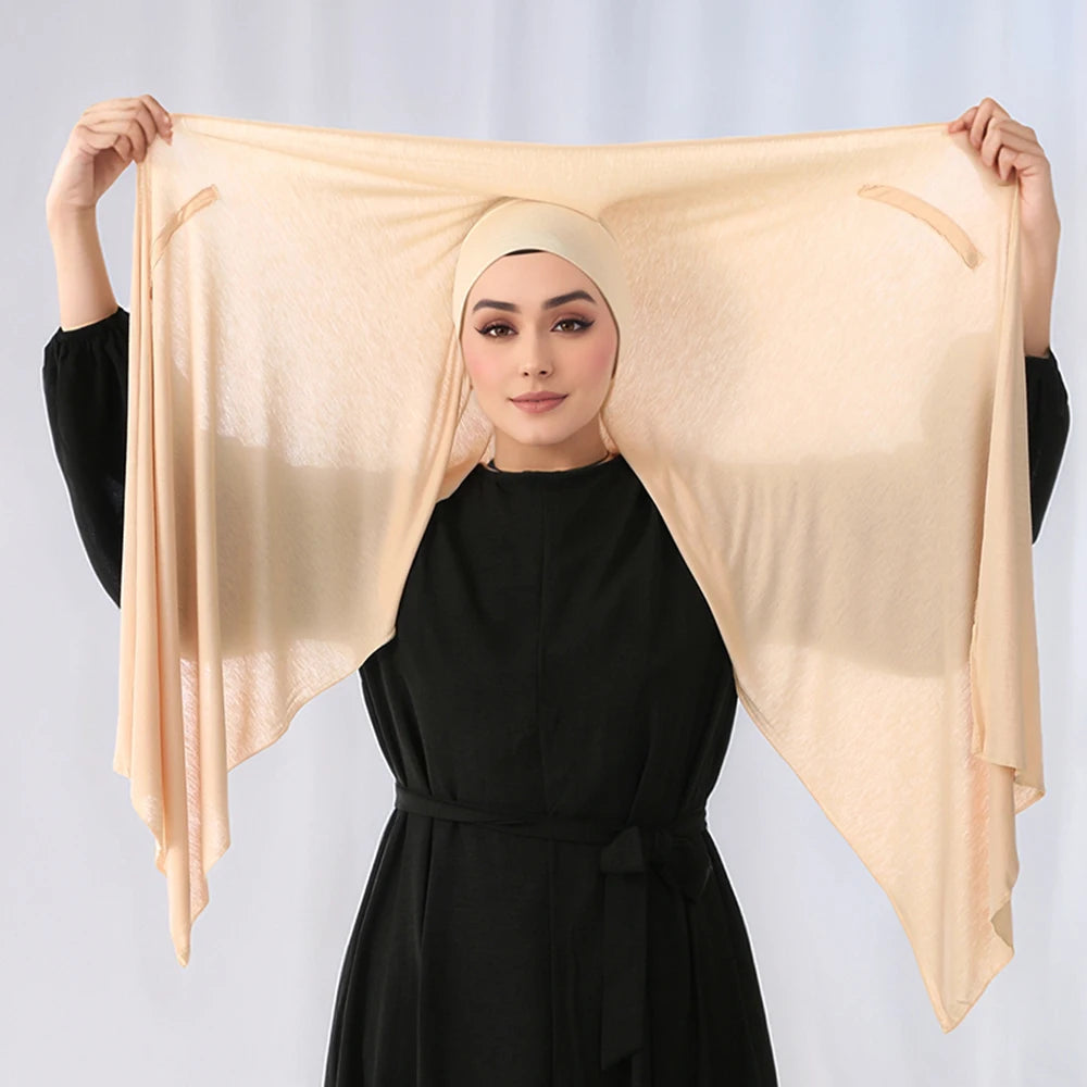 Eine Frau präsentiert einen eleganten beigeen Modal-Jersey-Hijab, der über ihren Kopf und ihre Schultern drapiert ist.
