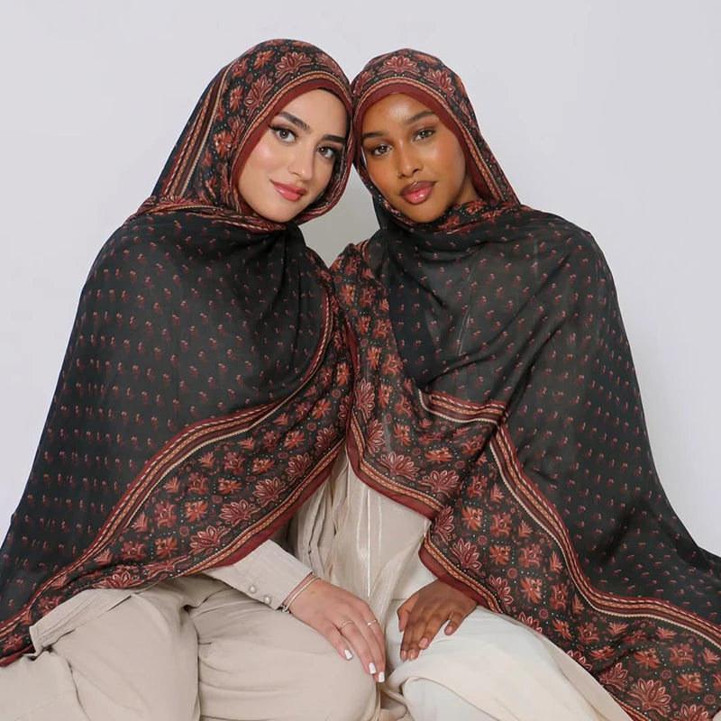 Zwei Frauen tragen dunkle braune Aquarell-Blumen-Hijabs und helle Kleidung.