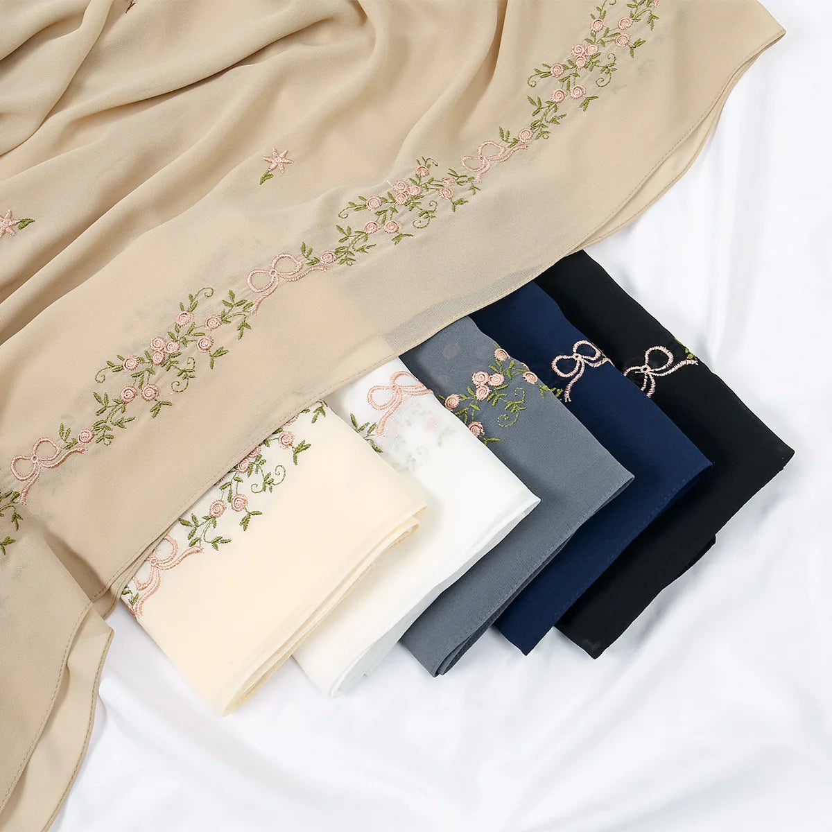 A beige chiffon hijab shawl with delicate pink floral embroidery displayed on a white background.