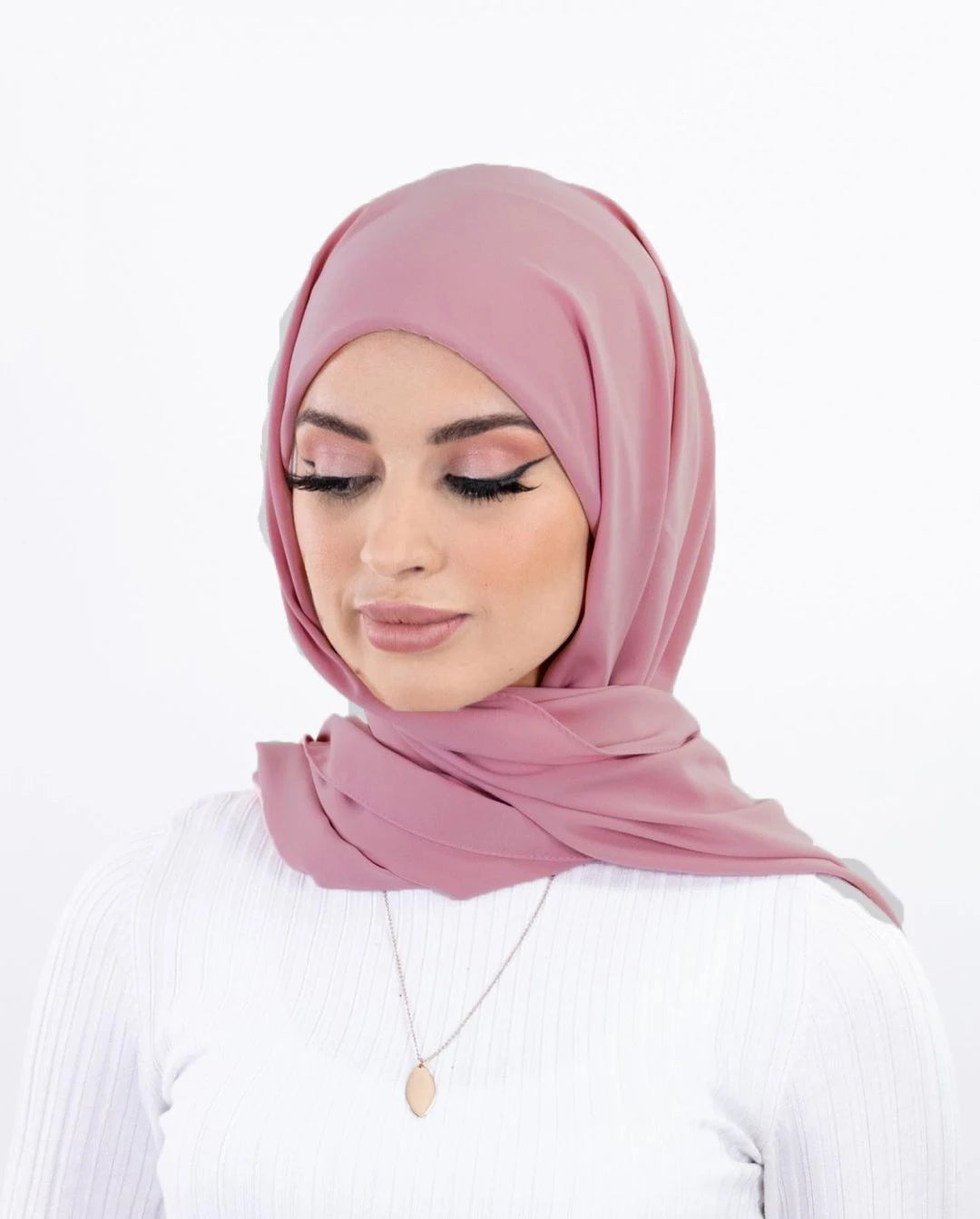 Une femme portant un hijab en mousseline rose poudré et un haut blanc.