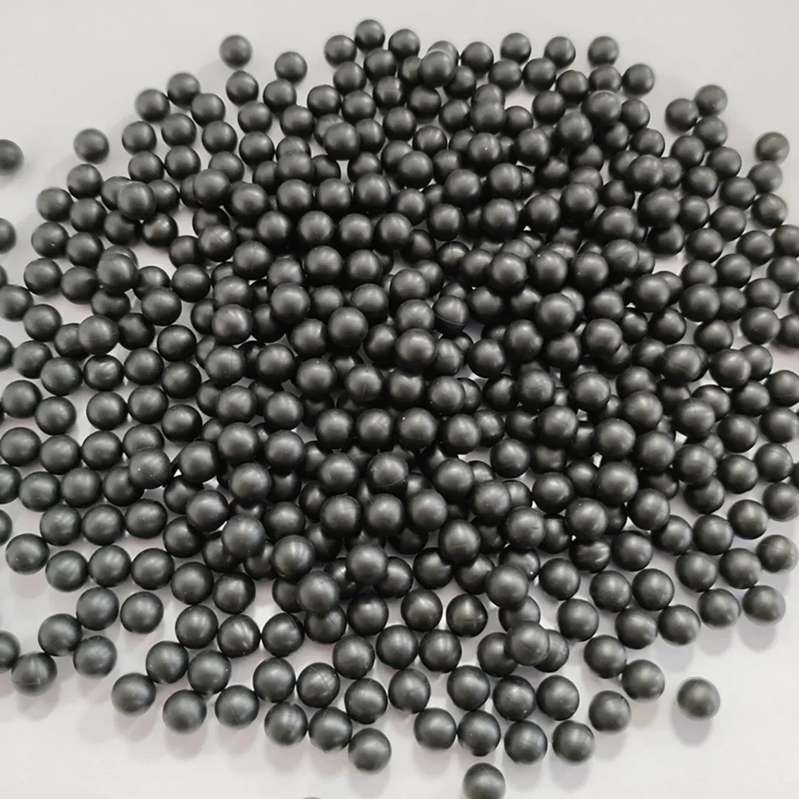 Haufen kleiner, dunkelgrauer oder schwarzer industrieller Gummi-Dichtungsbälle.