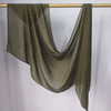 Foulard hijab modal vert olive transparent drapé sur un cintre doré.