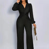 A woman models a black ribbed knit jumpsuit with a deep V-neck and puff sleeves.