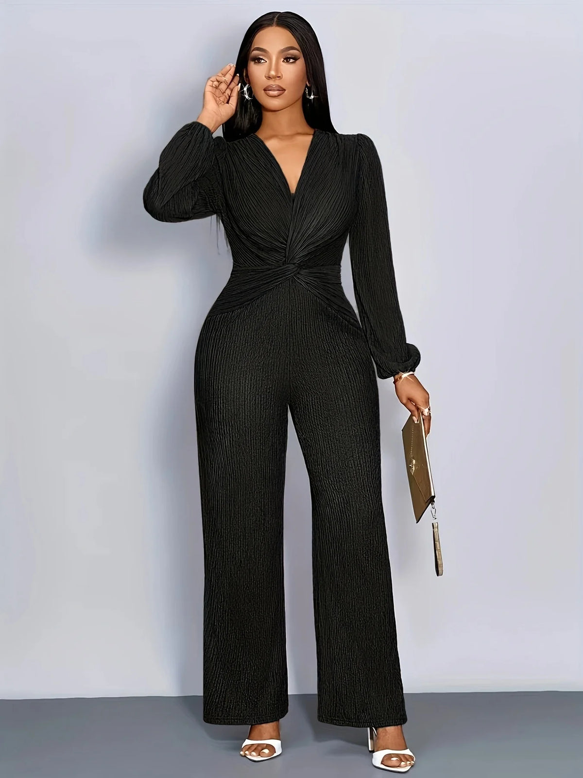 A woman models a black ribbed knit jumpsuit with a deep V-neck and puff sleeves.