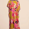 Una mujer vistiendo un caftán playero amarillo con estampado floral bohemio rosa y morado vibrante.