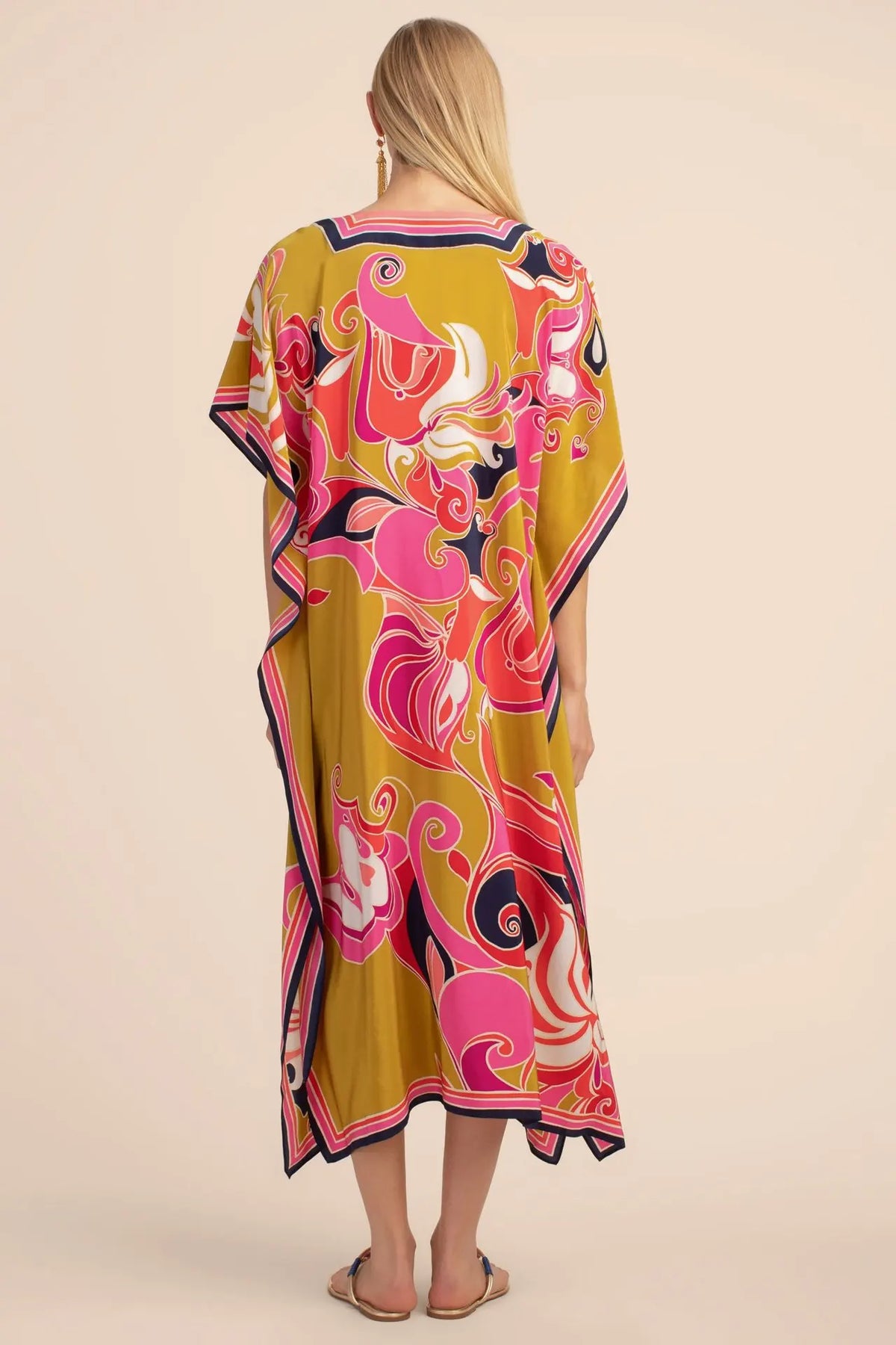 Una mujer vistiendo un caftán playero amarillo con estampado floral bohemio rosa y morado vibrante.