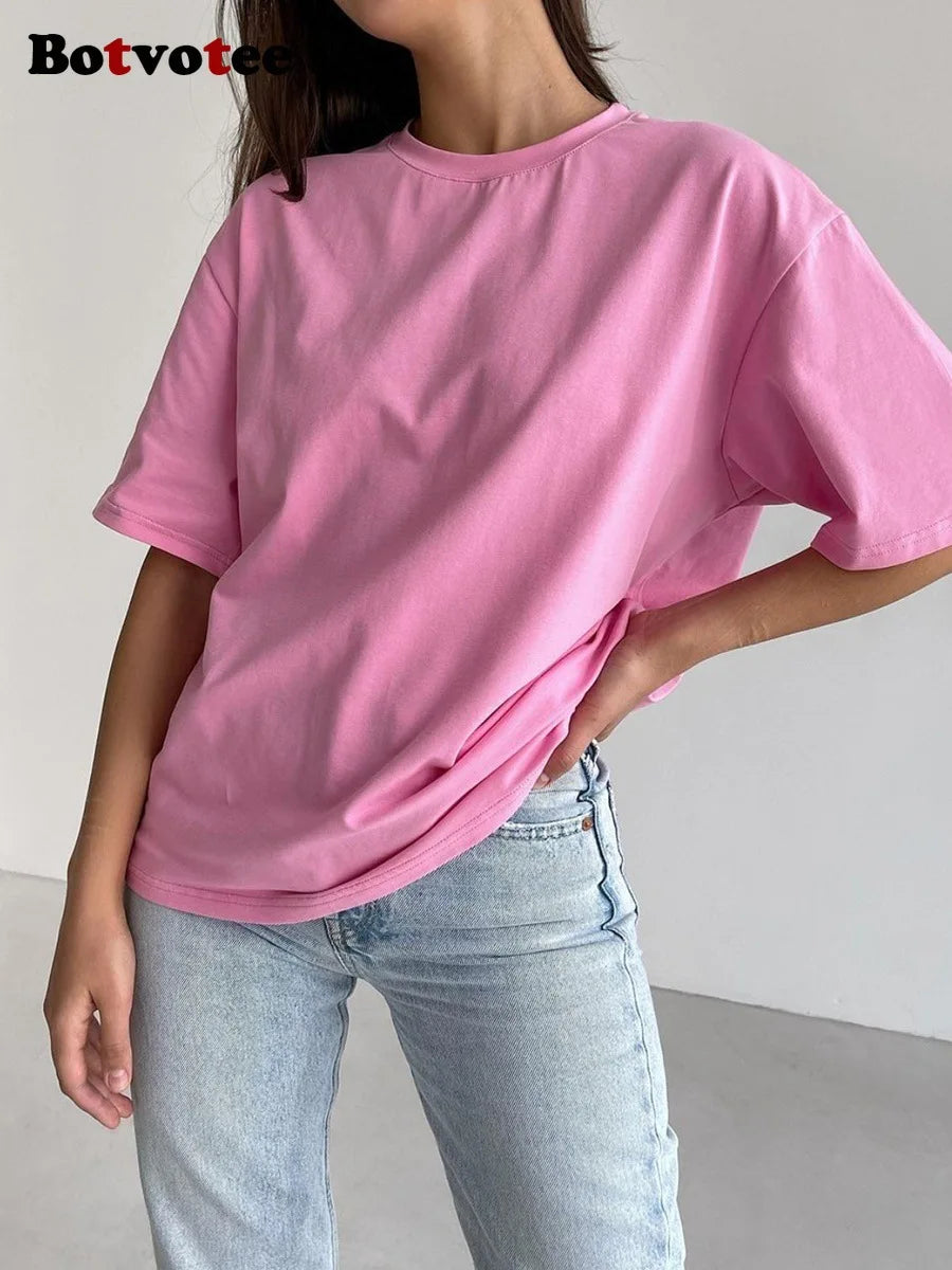 Una modelo vistiendo una camiseta básica de algodón rosa oversize y jeans de lavado claro.