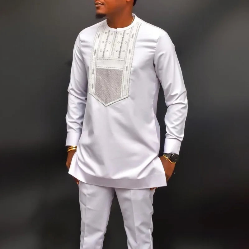 Un homme portant un costume de mariage musulman traditionnel africain blanc avec des détails brodés.