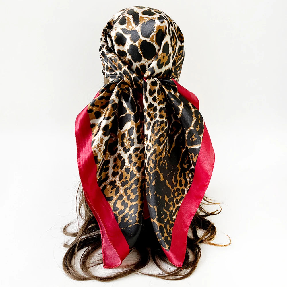 Pañuelo de seda cuadrado estampado leopardo negro y marrón atado alrededor de un cabello oscuro