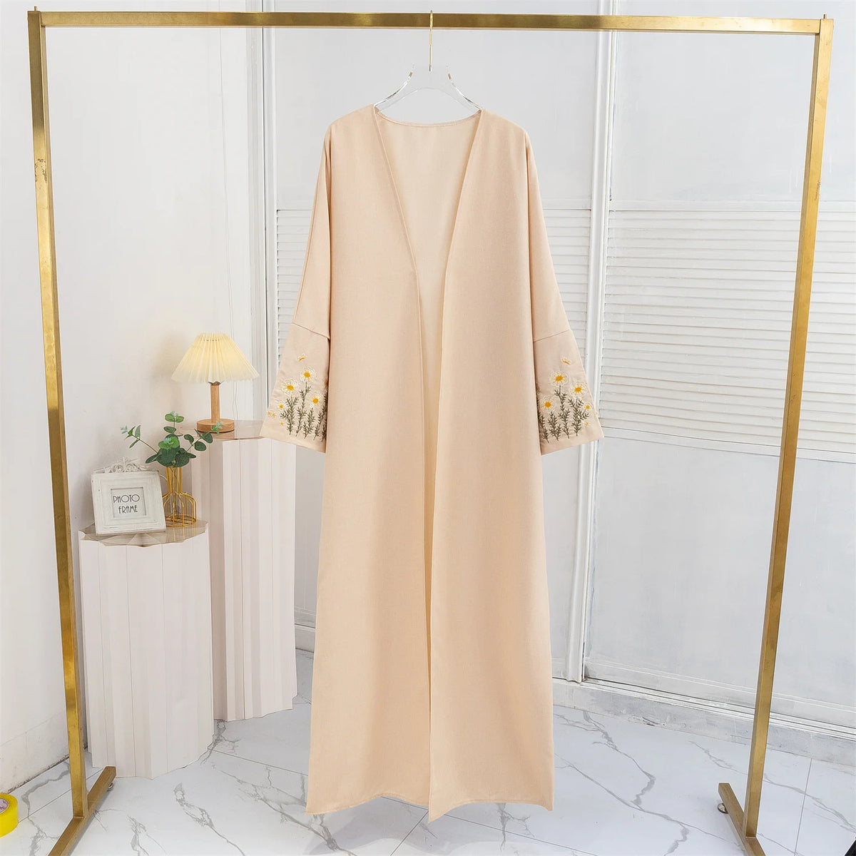 Beige, offene Maxikleid mit Blumenstickerei an den Ärmeln, aufgehängt.