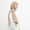 Eine Frau trägt einen beigen weichen Baumwoll-Jersey-Instant-Hijab und ein weißes Oberteil.