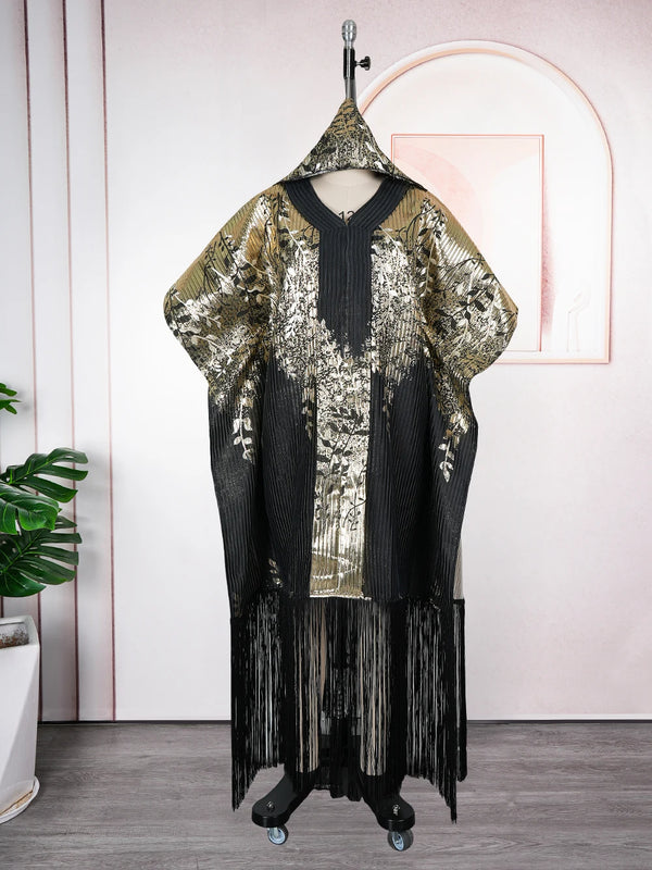 A black and gold traditional African dashiki maxi dress displayed on a hanger against a pink wall.