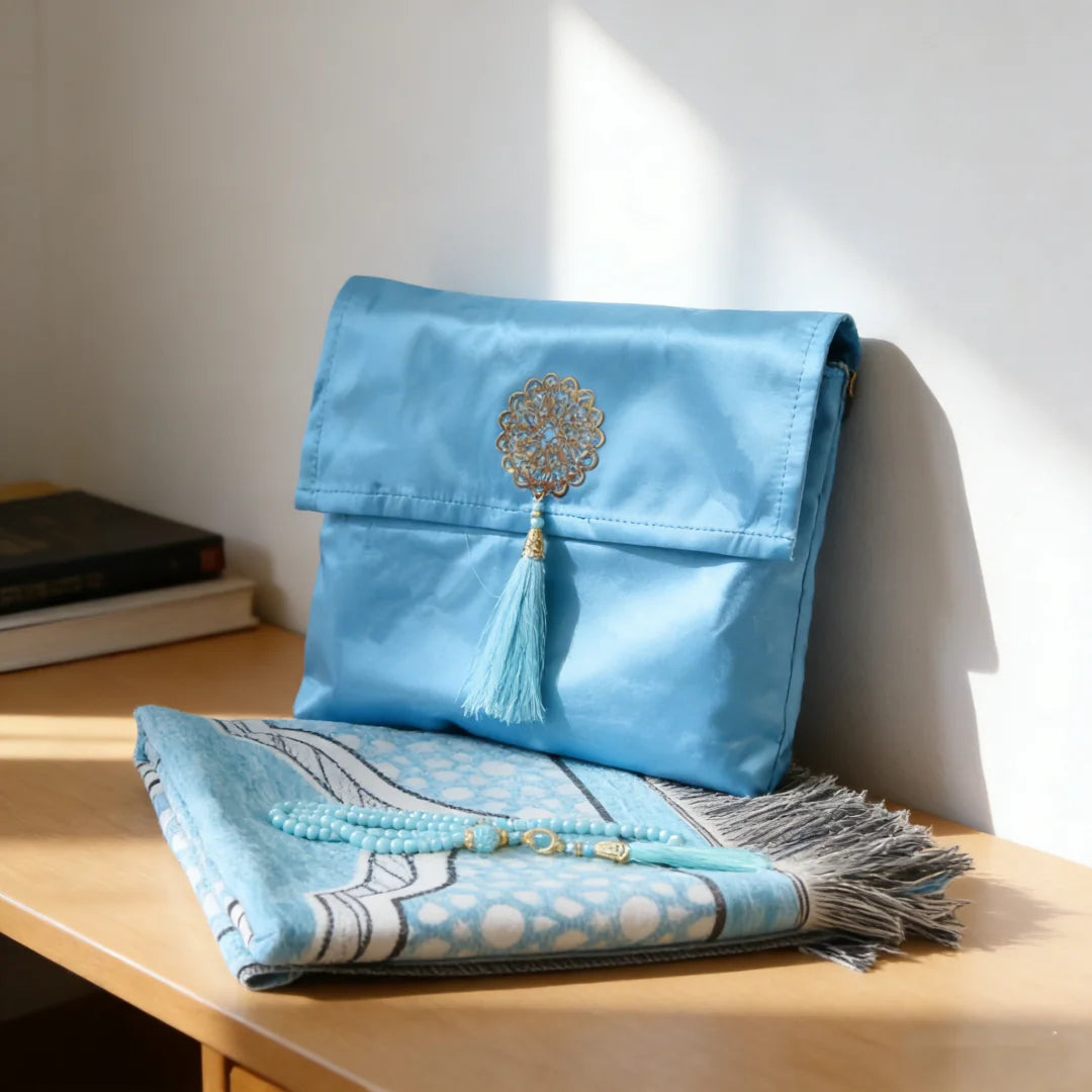 Una bolsa de tela azul claro con bordado dorado y borlas sobre una superficie de madera.