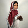 A woman wearing an elegant printed linen hijab scarf in maroon and white tones.