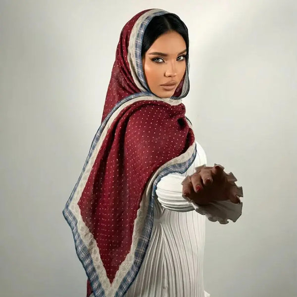 A woman wearing an elegant printed linen hijab scarf in maroon and white tones.