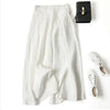 Weißer Leinenmisch-Crop-Palazzo-Hose in Creme neben einer schwarzen Clutch und weißen Schnürschuhen.