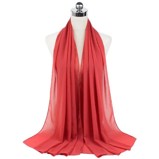 A vibrant coral red chiffon hijab scarf draped on a mannequin.