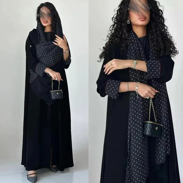 A woman models an elegant black abaya cardigan dress with a polka dot pattern and long sleeves.