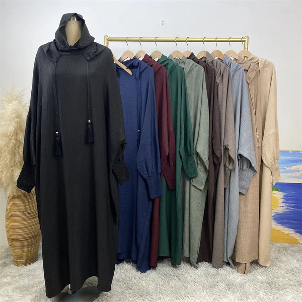 A multi-color abaya with a hood and batwing sleeves displayed on a wooden hanger against a white background.