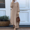 Una mujer vistiendo un conjunto abaya de manga larga beige de camisa, de pie frente a una puerta blanca.