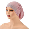 Una modelo lleva un hiyab elástico color rosa empolvado adornado con detalles de purpurina plateada.
