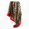 Pañuelo de seda cuadrado estampado de leopardo negro y dorado, drapeado verticalmente.