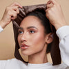 A woman is adjusting an elegant satin hijab cap and undercap set on her head.