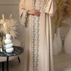 Elegante beige Abaya mit dezenter Blattstickerei, getragen von einem Model.