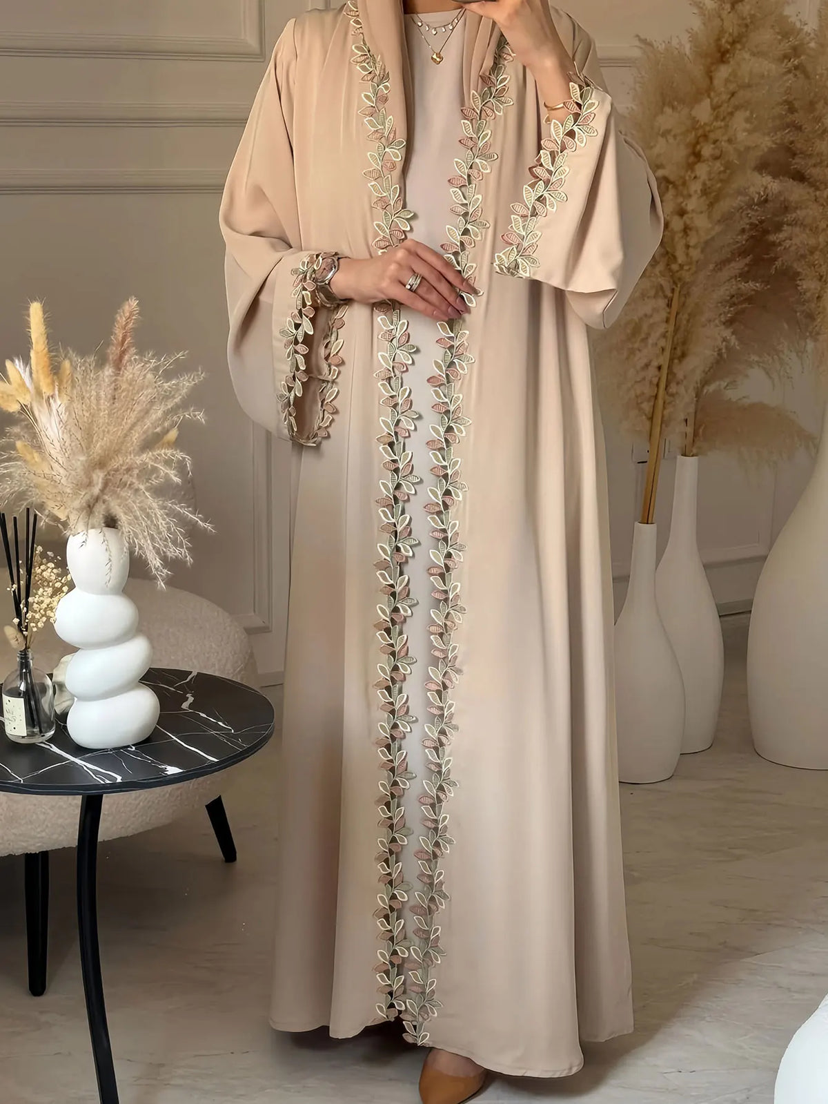 Elegante beige Abaya mit dezenter Blattstickerei, getragen von einem Model.