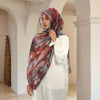 Eine Frau mit aquarelliertem Chiffon-Hijab und weißem Kleid steht in einem bogenförmigen Raum.